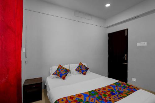 チェンナイにあるFabHotel Pavis Innの白いベッドとカラフルな枕のある寝室