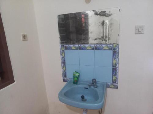 a bathroom with a blue sink and a mirror at Hotel O Endj Walet Samodra in Tepus