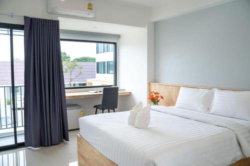 Un dormitorio con una cama y un escritorio y una ventana. en Meesuk ChiangRai Hotel, en Chiang Rai
