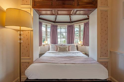 ein Schlafzimmer mit einem großen Bett mit einem großen Fenster in der Unterkunft Tiverton Bungalow in Udagamandalam