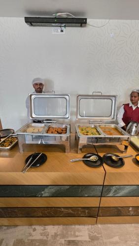 two people in a kitchen with several trays of food at Elite Hotel Karimnagar in Kottapalli