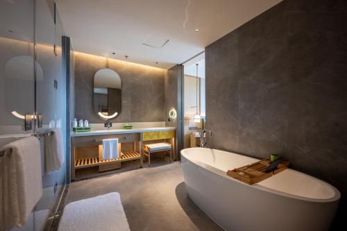 een badkamer met een wit bad, een wastafel en een bad bij Holiday Inn Pu'er Jingmai by IHG in Mengman