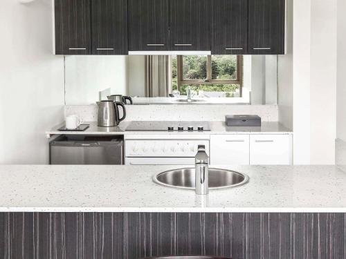 a kitchen with a sink and a stove at Mantra on Jolimont Melbourne in Melbourne