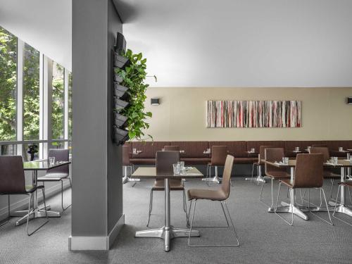 a dining room with tables and chairs and windows at Mantra on Kent in Sydney