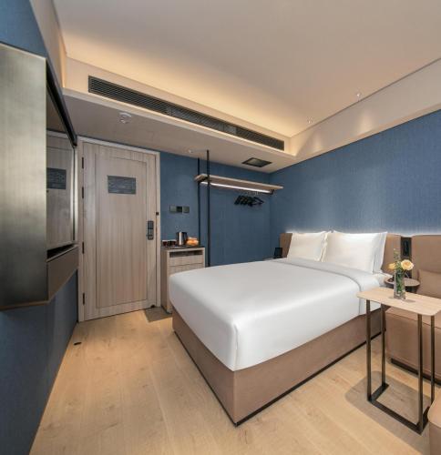 a bedroom with a white bed and a blue wall at Orange Hotel Beijing Zhongguancun Software Park in Beijing