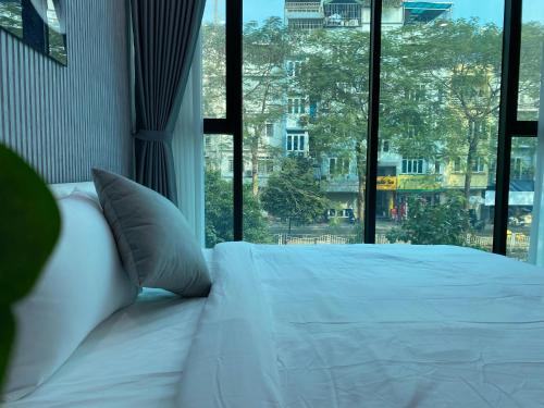 a bed with white sheets and pillows in front of a window at Grand C Homestay in Hanoi