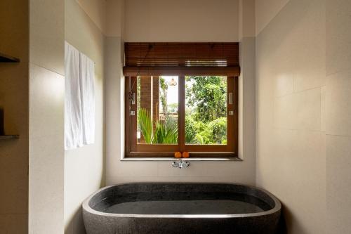 een badkuip in een badkamer met een raam bij Orchid Ubud Cottage in Ubud