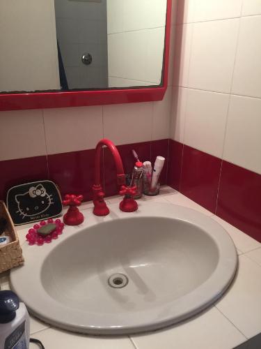 a bathroom sink with a red faucet and a mirror at Giulianahouse in La Maddalena
