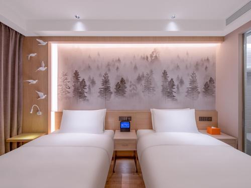 two beds in a room with a painting on the wall at Orange Hotel Beijing South Railway Station South Square in Beijing