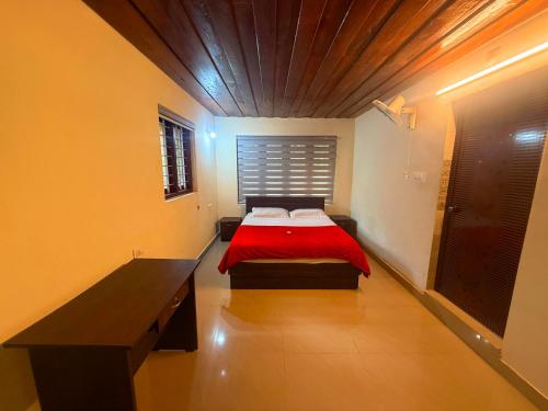 a bedroom with a bed with a red blanket at Wayanad Shas Villa in Padinjarathara