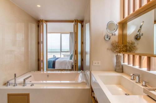 une salle de bain avec une grande baignoire et un grand miroir dans l'établissement Ace of Hua Hin Resort - One Bedroom Ace Seaview Suite Private Pool, à Sathani Huai Sai Tai