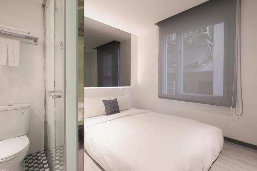 a small bedroom with a bed and a toilet at CityInn Hotel Plus - Taichung Station Branch in Taichung