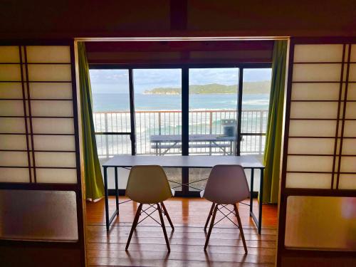 a table and two chairs in a room with a balcony at コンドミニアム海のまんまえ荘 in Ōda