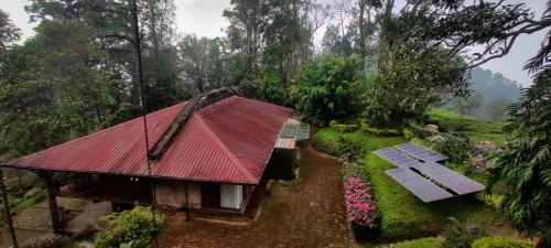 une petite maison avec un toit rouge et un banc dans l'établissement RGS Bungalow Munnar, à Devikolam