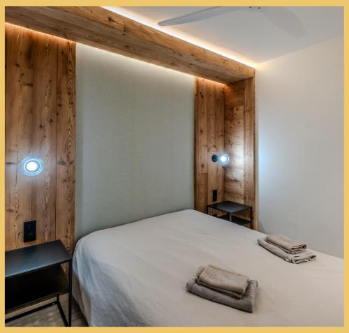una camera da letto con un letto bianco e pareti in legno di L'Élégance Alpine I Centre Les Gets a Les Gets