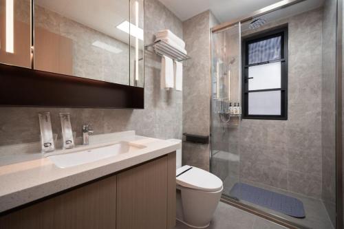 a bathroom with a toilet and a sink and a shower at 来咖民宿酒店三亚市中心大悦城店 in Sanya