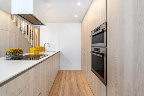 a kitchen with white countertops and a black oven at Riverside duplex by the sea with pool and balcony in Fão