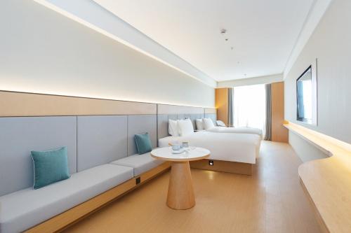 ein Hotelzimmer mit einer Couch, einem Bett und einem Tisch in der Unterkunft JI Hotel Shanghai Caohejing Hongcao Road in Shanghai