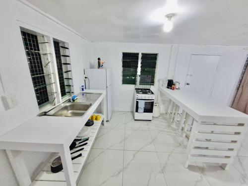 eine weiße Küche mit Spüle und Kühlschrank in der Unterkunft Kava Cottage - Entire Place in Nuku‘alofa