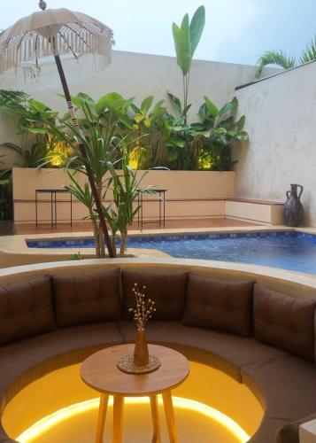 a living room with a couch and a table in front of a pool at Andara Villa Yogyakarta in Yogyakarta