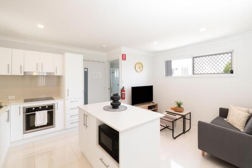 a white kitchen and living room with a couch at Smart Suites Self Check-in Apartments - S Freney in Brisbane