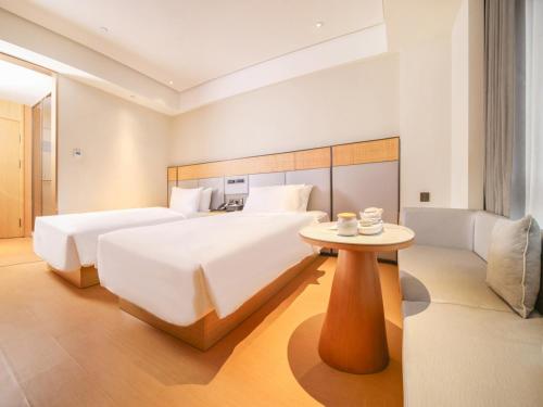 1 Schlafzimmer mit 2 Betten, einem Tisch und einem Sofa in der Unterkunft JI Hotel Shanghai Central Ring Bailian Meichuan Road (formerly Meichuan Road Branch) in Shanghai
