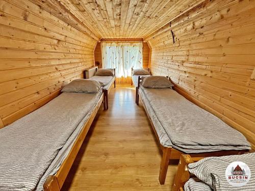 een rij bedden in een kamer met houten wanden bij Bucsin menedékház in Bucin