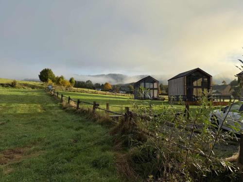 a field with a fence and houses in a field at Pod Stromcem in Czernica