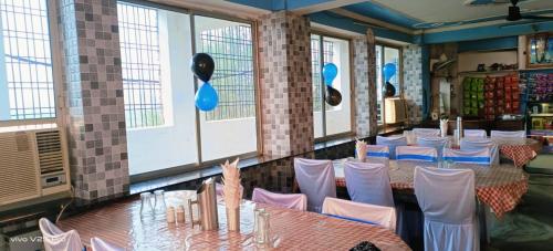 une salle à manger avec tables, chaises et fenêtres dans l'établissement Hotel New Gurudeo Basera And Family Restaurant, à Aurangābād