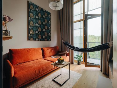 an orange couch in a living room with a hammock at Sume by Larsen in Tallinn