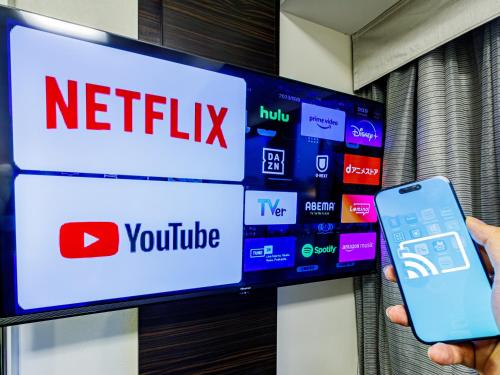 東京にあるアパホテル〈東京大島〉のテレビの前で携帯電話を持っている人