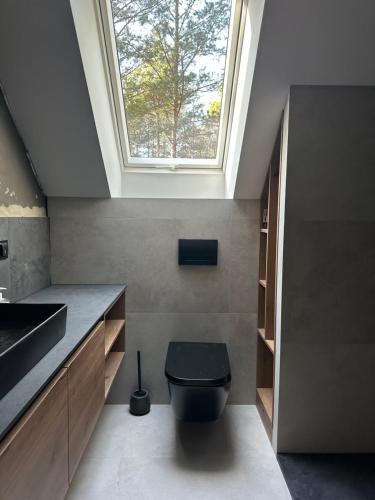 a bathroom with a black toilet and a skylight at Chata w Puszczy Nowa Łuka in Łuka