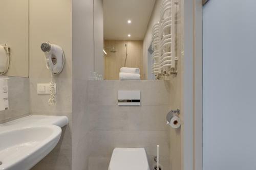 a white bathroom with a toilet and a sink at Hotel Zatoka in Gdańsk