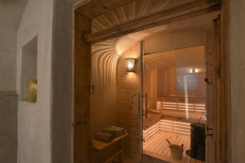 a bathroom with a glass door leading to a sauna at B&B Mas de Lagorae in Tesero