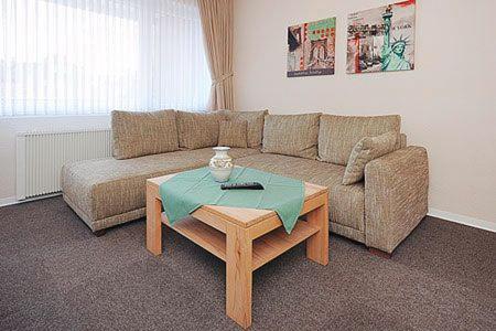 uma sala de estar com um sofá e uma mesa em Ferienwohnungen Alter Sielweg Wohnung 10 em Bensersiel