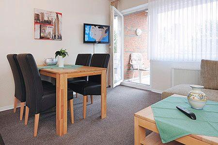 uma sala de estar com uma mesa de jantar com cadeiras em Ferienwohnungen Alter Sielweg Wohnung 10 em Bensersiel