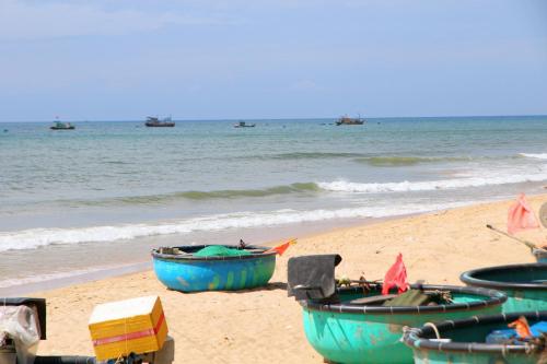 three boats sitting on a beach with the ocean at Villa Biển Vàng Beach Front in Bình Sum