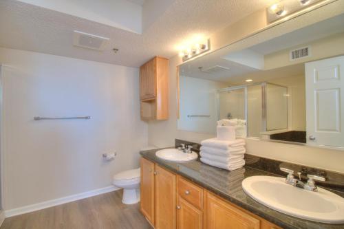 a bathroom with two sinks and a toilet and a mirror at Crescent Shores South - 612 in Myrtle Beach