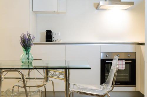 a glass table with chairs and a vase of flowers at Zambianchi Studio - Sostify in Bergamo