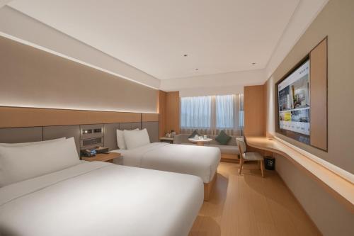 una camera d'albergo con due letti e una TV a schermo piatto di JI Hotel Beijing South Railway Station North Square a Pechino