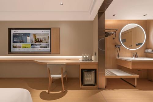 bagno con lavandino e scrivania con specchio di JI Hotel Beijing South Railway Station North Square a Pechino