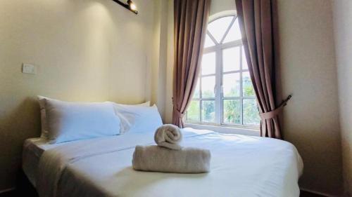 a white bed with a towel on it in front of a window at Swing and Pillows - Jalan Changkat Thambi Dollah in Kuala Lumpur