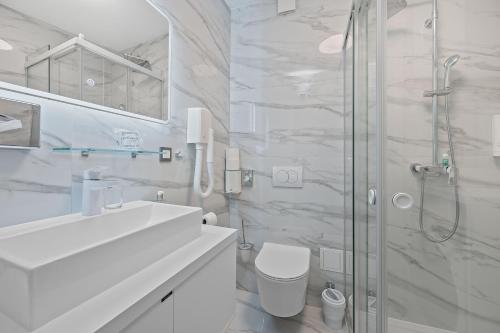 a white bathroom with a sink and a shower at Apartmani Point Pregrada in Pregrada