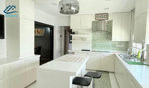 a white kitchen with white cabinets and a sink at Landed Spacious House at Cangkat Delima Gelugor Penang in Gelugor