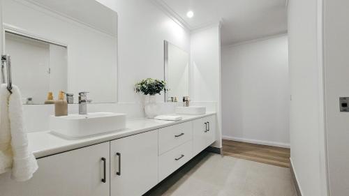 a white bathroom with two sinks and a mirror at Kincaid Travellers Townhouse - Central Wagga in Wagga Wagga