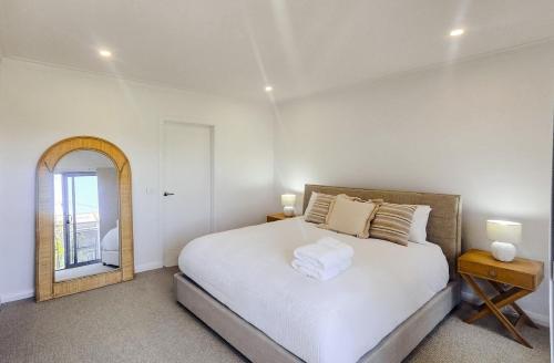 a white bedroom with a bed and a mirror at Kincaid Travellers Townhouse - Central Wagga in Wagga Wagga