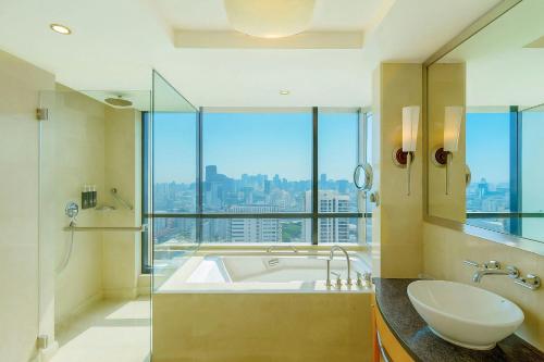a bathroom with a tub and a sink and a window at The Westin Dhaka in Dhaka