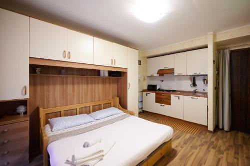 een slaapkamer met een bed en een keuken met witte kasten bij Mono Villaggio Del Sole in Limone Piemonte