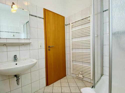 een badkamer met een wastafel en een glazen deur bij Villa Fortuna Gästehaus App Hiddensee in Ahlbeck