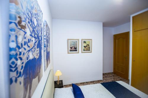 a bedroom with a bed and a wall with paintings at PLUMA VILLA - Only Families in Salou